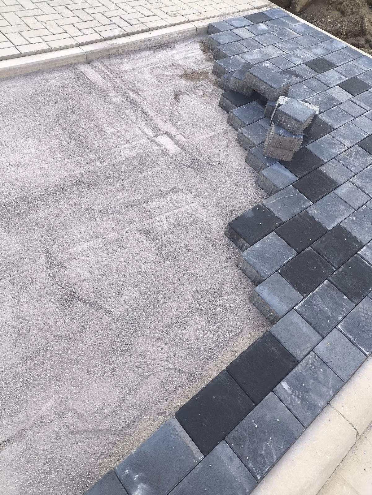 Betonpflaster in Anthrazit wird auf dem abgezogenen Splittbett verlegt