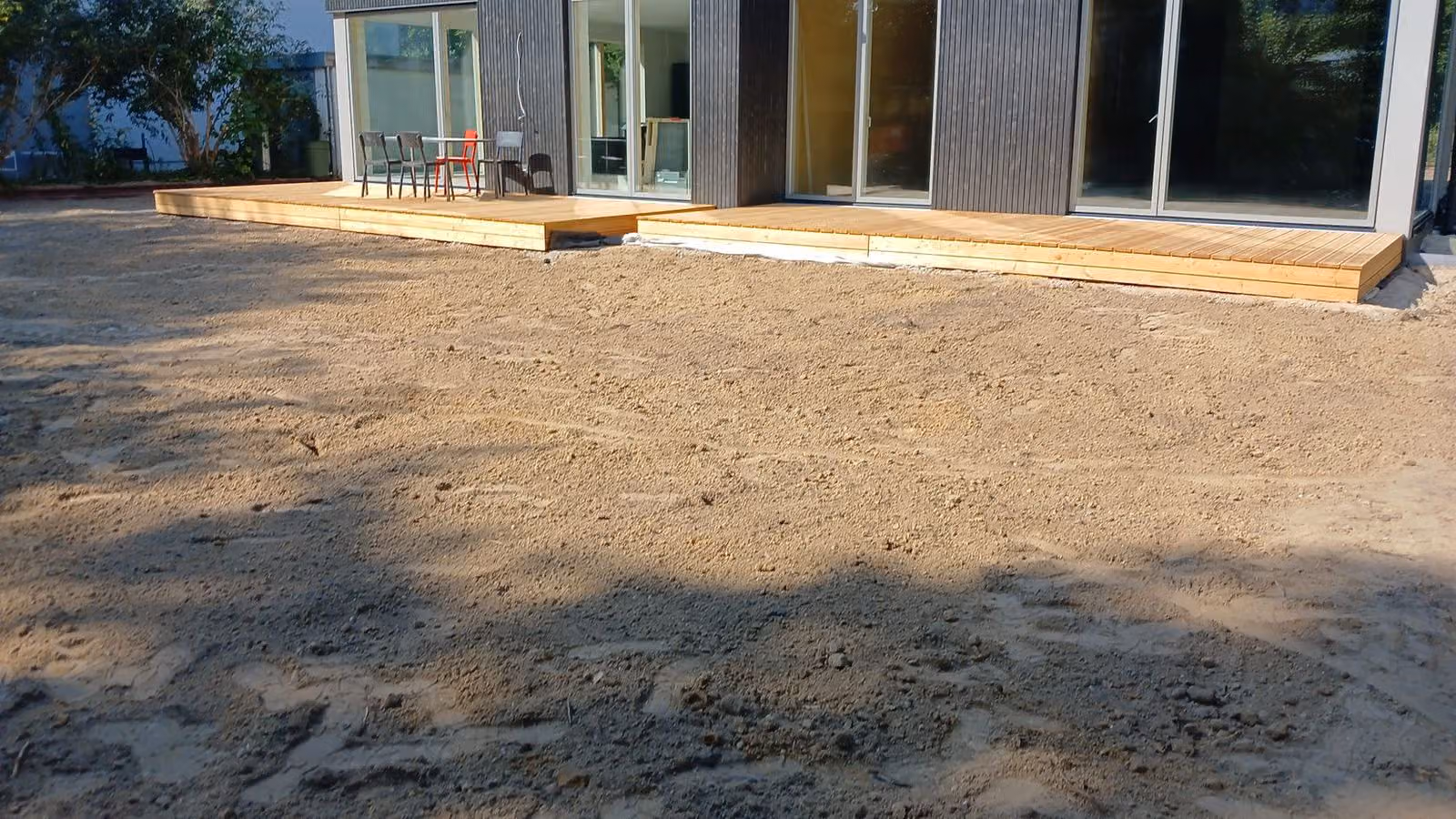 Fertige Holzterrasse am Haus, davor das abgezogene Planum für den Rasen