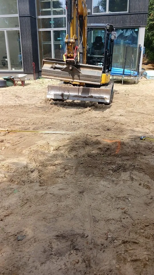 Minibagger zieht ein Sandplanum auf einer Neubaufläche ab