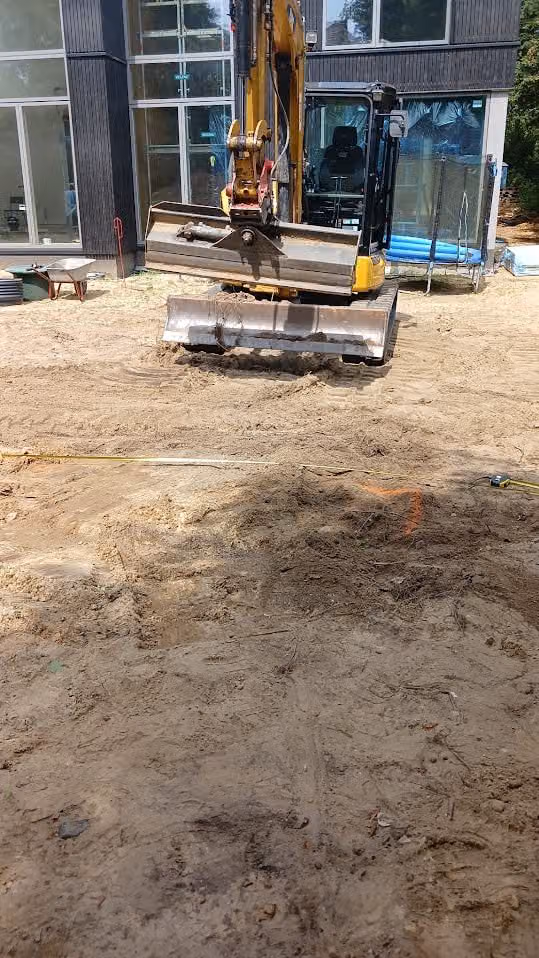 Minibagger und Plattenmaterial auf dem Sandplanum während der Bauphase