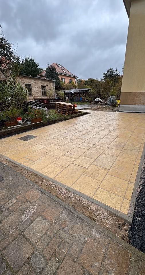 Fertige Terrasse aus hellen Travertinplatten am Haus, Randeinfassung und Kiesstreifen gesetzt